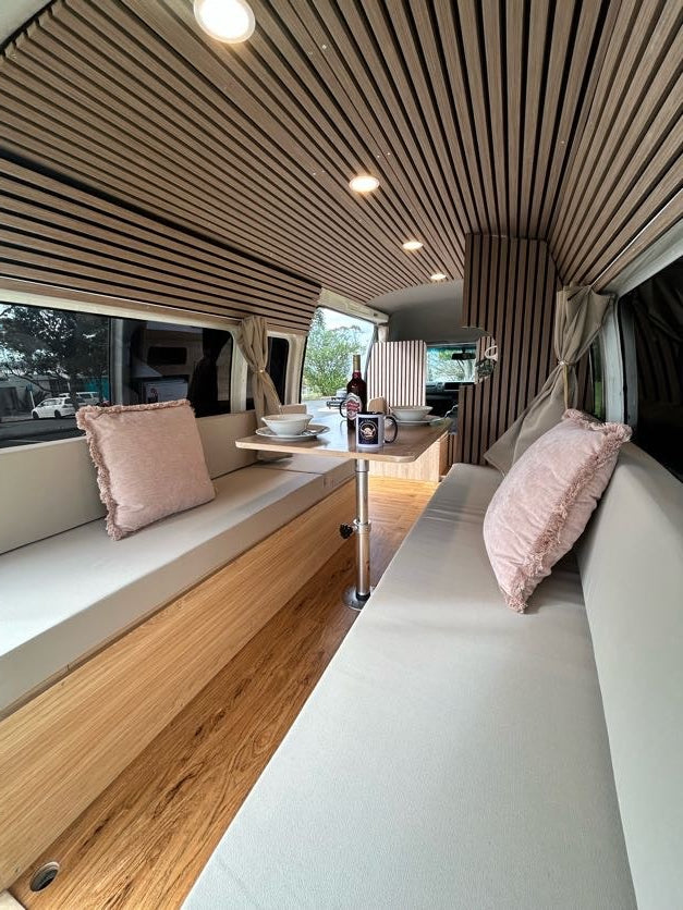 Hiace Jumbo campervan lounge with slat-panelled walls and made-up benches